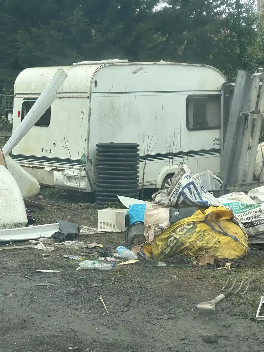 Outdoor site with caravan and mixed clearance materials